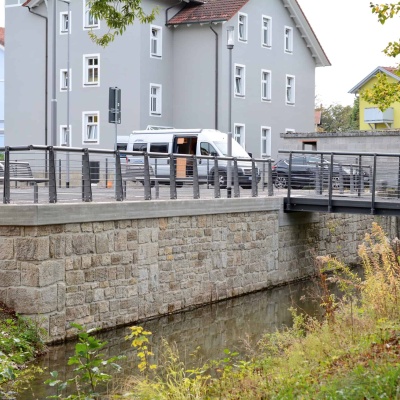 Parkplatz, Ufermauer und Fußgängerbrücke am Bleichgraben in Meiningen